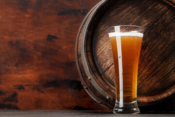 Glass of light lager beer and old wooden barrel
