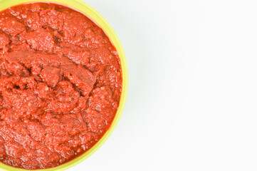The crop image of grinded chili pepper in a green bowl isolated on a white background.