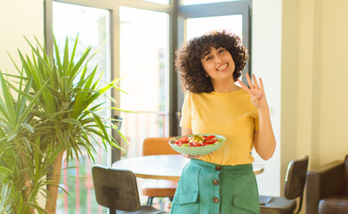 young pretty woman smiling and looking friendly, showing number four or fourth with hand forward,...