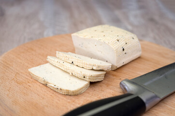 tofu cheese on a wooden board and a knife.