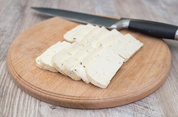 tofu cheese on a wooden board and a knife.