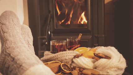 mulled wine by the fireplace, 2 glasses of drink, spices, a warm scarf and feet in warm socks near the stove