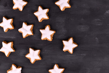 Fototapeta na wymiar German star shaped glazed cinnamon Christmas cookies called 'Zimtsterne' on dark black ackground