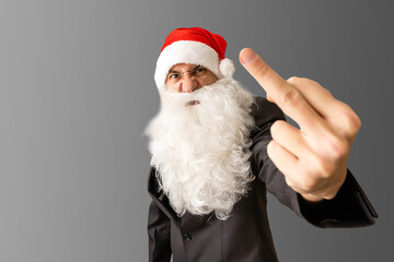 Middle age handsome man wearing Santa Claus costume and beard standing Showing middle finger doing fuck you bad expression, provocation and rude attitude. Screaming excited