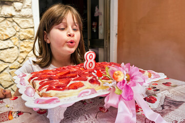 Young girl blowing out candles