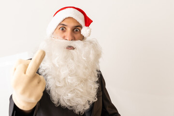 Middle age handsome man wearing Santa Claus costume and beard standing Showing middle finger doing fuck you bad expression, provocation and rude attitude. Screaming excited