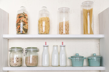 Various uncooked groceries in glass jars on shelf in kitchen