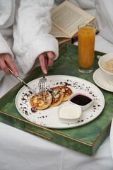 Woman reading book while having breakfast in bed.