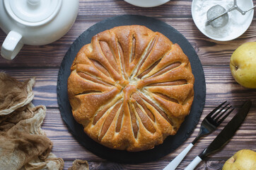 Pie with pears and powdered sugar on a board