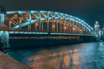 the beautiful metal bridge of Peter the Great across the Neva River in St. Petersburg against the night sky