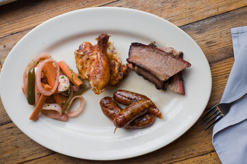 Barbecue catering platter with variety of meats. Traditional Texas BBQ: Beef brisket, beef ribs, pork ribs, sausage links, black pepper roasted chicken, and turkey served with homemade sauce.