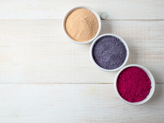 Set of superfoods in white bowls on wooden background.