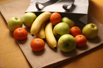 Bananas tangerines and apples with paper bag on linen background