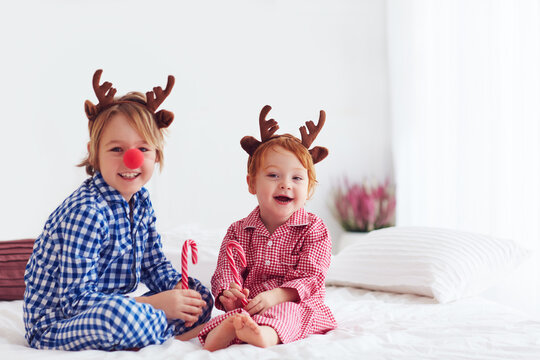 laughing kids, brothers wearing reindeer antlers celebrate christmas holidays at home