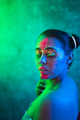 Ultraviolet paint on face of sexy young woman in blue and green colors. Ethnic, esoteric and art concept.