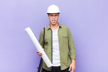 young blonde man feeling disgusted and irritated, sticking tongue out, disliking something nasty...