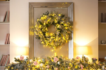 Traditional wreath with fairy lights hanging on door in cozy room during Christmas celebration at home