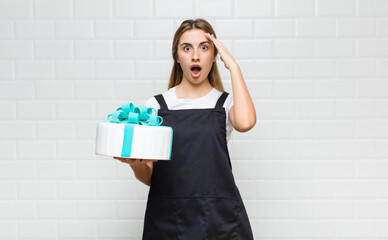 blonde pretty woman looking happy, astonished and surprised, smiling and realizing amazing and...