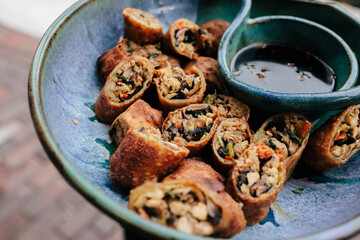 Vegetable spring rolls served on blue porcelain dish with soy sauce for sipping
