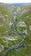 Aerial drone view above Sohodol Gorges. A road wides along the river through its tight rocky canyon. Carpathia, Romania.