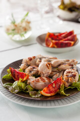 Grilled Frog Legs Garnished with Blood Orange Slices and Fresh Lettuce