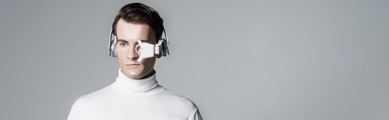 Cyborg in digital eye lens and headphones isolated on grey with copy space, banner