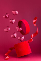 Flying red velvet box with red silk ribbon, red glitter paper hearts fly frome box, vertical
