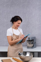 Woman chef in the kitchen is writing down recipe for new dish. Smiling Chef. Vertical frame