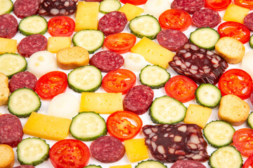 sliced ​​pieces of sausage, salami, cheese, cucumber and tomato. fast food. ingredients for pizza. calories and diet