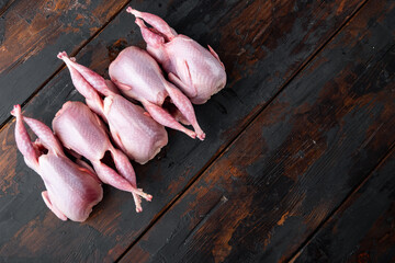 Fresh organic whole quails meat, top view, on dark wooden background  with copy space