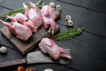 Whole quails with spices, herbs, vegetables, on black wooden background  with copy space