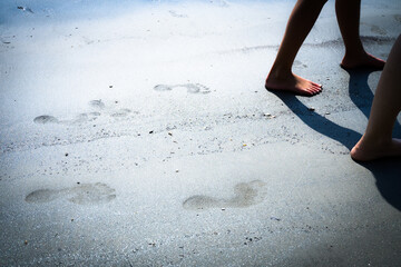 zwei Personen gehen Barfuß am Strand im Sand, Fußspuren nebeneinander im Sand, Fußabdrücke im...