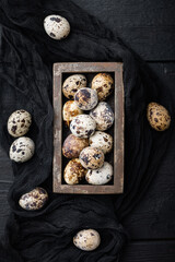 Obraz na płótnie Canvas Organic quail eggs, top view, on black wooden background
