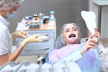 The dentist performs professional dental cleaning and oral hygiene. A young girl at a dentist...