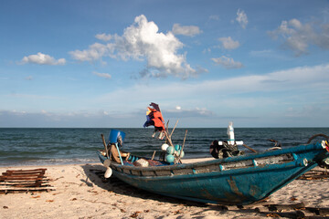 Naklejka na ściany i meble fishing boat on a lonesome beach with white sand and blue water somewhere in Thailand
