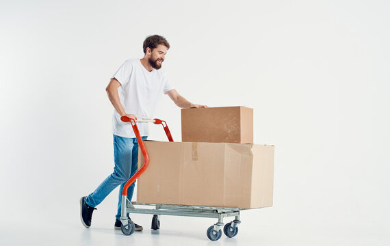 bearded male courier with cardboard boxes on a cargo trolley