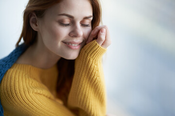 pretty woman in a yellow sweater hiding behind a blanket near the window comfort home interior