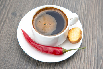 white Cup of black coffee and red hot pepper with biscuits on a wooden frame