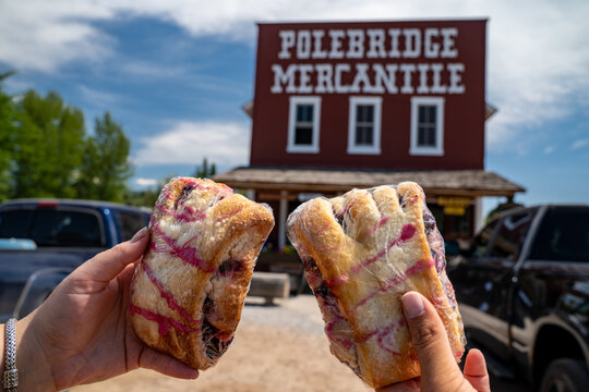 Polebridge, Montana - July 28, 2020: The famous Polebridge Mercantile, a bakery and shop in the small community in Glacier National Park. Hand holds up a famous huckleberry bear claw