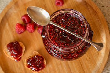 homemade rasberry Jam in Jar with Spoon / rasberries Marmalade served with Bread Slices in Wicker Bowl.
