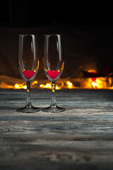 Champagne glasses with red hearts on a dark background. Side view with space for copying. Concept of holiday backgrounds, love.