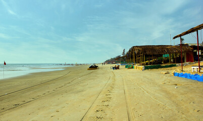 Wide angle shot of a beach with nobody with restaurant hut or shed located on a beach of Goa in India against blue sky
