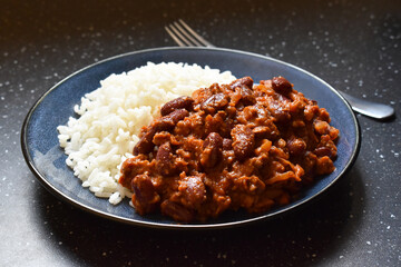 Chilli con carne with rice on a blue plate.  Traditional Mexican food. 