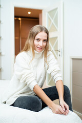 Close up portrait of blonde young woman wearing sweater at home