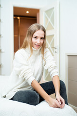 Fototapeta premium Close up portrait of blonde young woman wearing sweater at home
