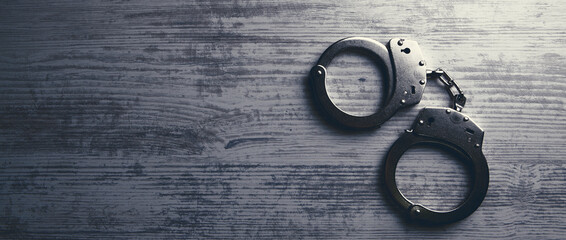 Isolated handcuffs, banner and copy space on a wooden background.