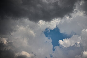 blue sky window, surrounded by white and gray clouds.
