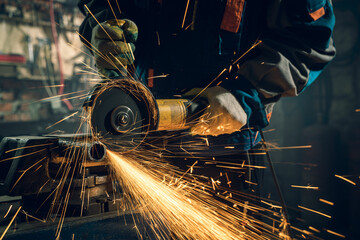 Locksmith in special clothes and goggles works in production. Metal processing with angle grinder....