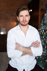 Portrait of a handsome man against the background of Christmas garlands and a Christmas tree