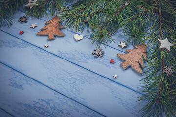 Christmas or New Year background: pine branches and wooden decorations on the blue boards